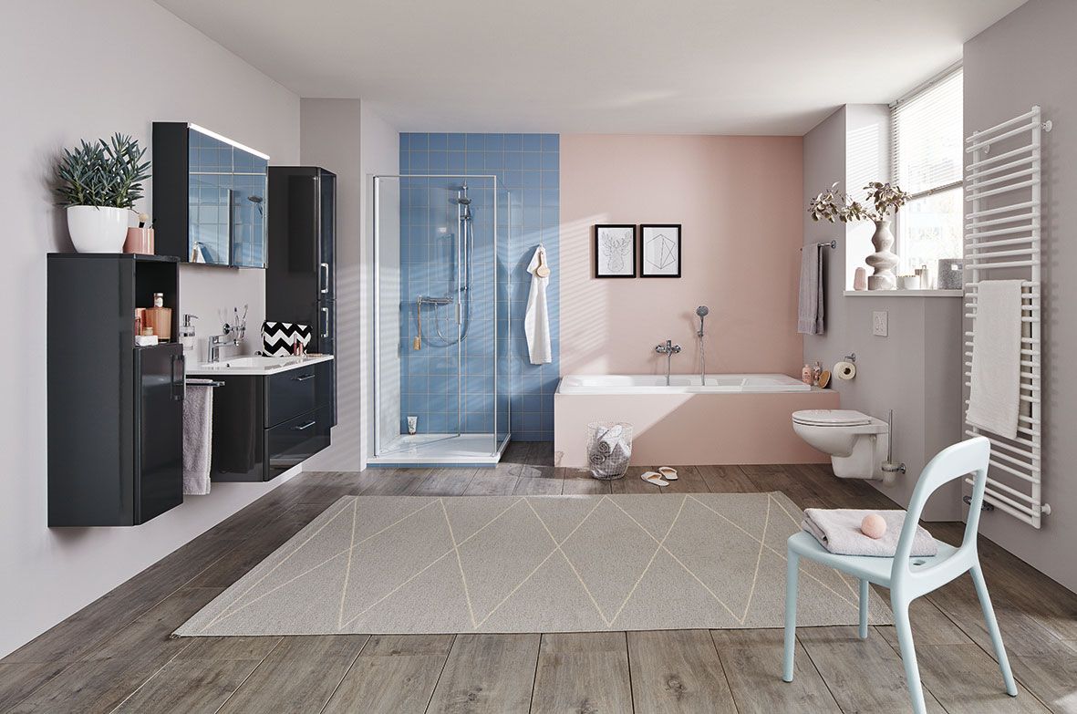 in Badezimmer mit einer weißen Toilette, schwarzem Waschbecken, blauer Dusche, rosa Badewanne und einem hellblauen Stuhl.